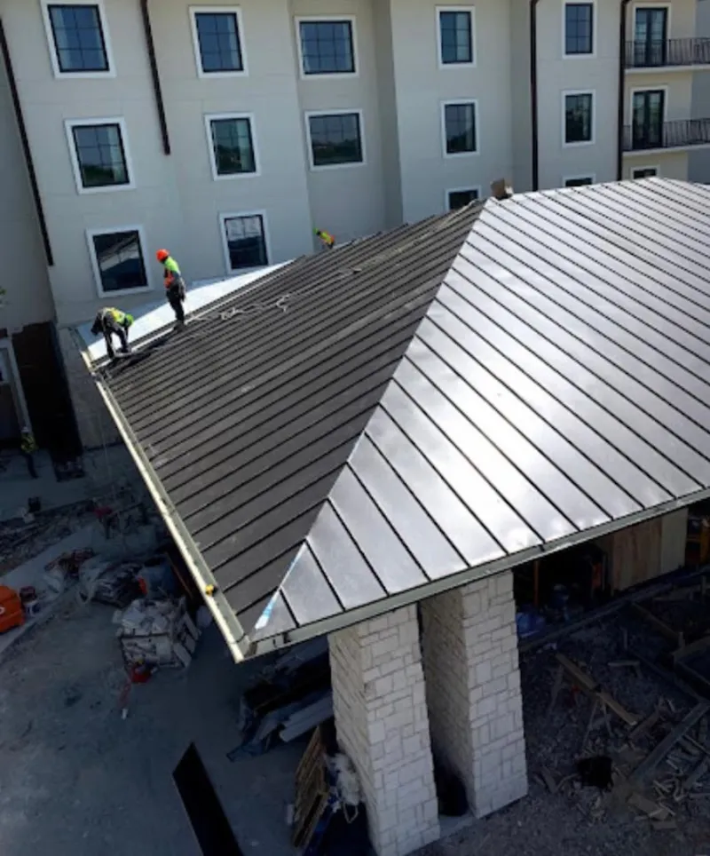 Crew installing standing seam metal roof panels on a commercial project in Haddon